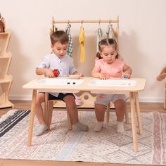 two children sitting at a table playing with toys