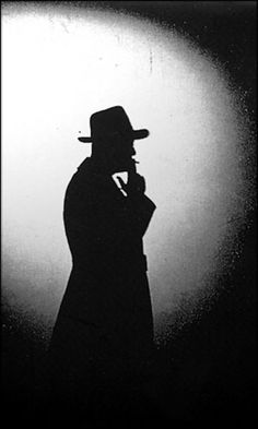 the silhouette of a man in a hat and coat