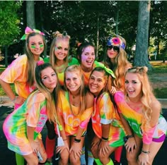 a group of young women standing next to each other wearing rainbow colored shirts and shorts