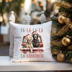 two dogs sitting in the back of a red truck on a christmas pillow next to a tree