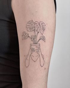 a woman's arm with a tattoo on it and a plant in the vase