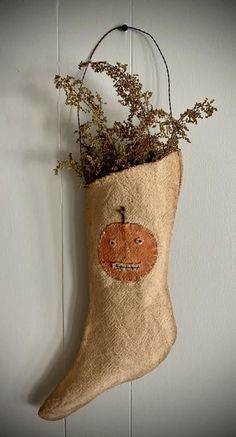 a stocking hanging on the wall with a plant in it's mouth and an orange face