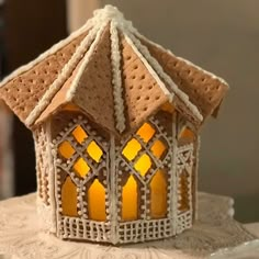 a lit up gingerbread house sitting on top of a white doily covered table