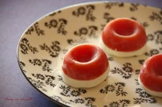 three small donuts on a plate with black and white designs around the edges, ready to be eaten