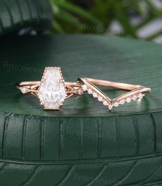 two wedding rings on top of a green tire, one with an oval diamond and the other with small round diamonds