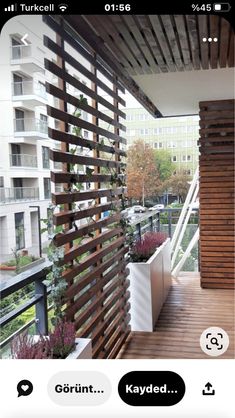 an iphone screenshot of a balcony with plants on the railing and buildings in the background