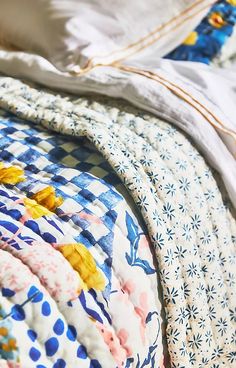 an unmade bed with blue and white quilts