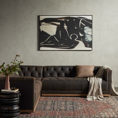 a living room with a couch, rug and large painting on the wall above it