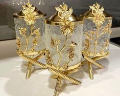 three vases with gold flowers on them sitting on a table