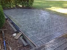 an outdoor patio being built with bricks and wood in the ground, surrounded by shrubbery