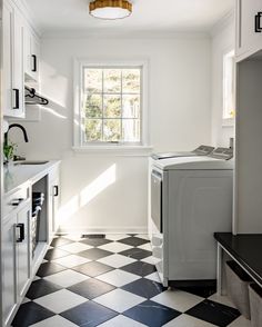 a kitchen with black and white checkered flooring next to a washer and dryer