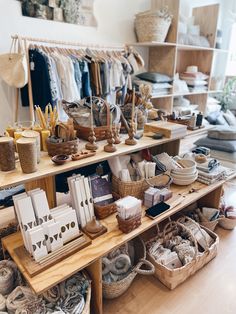 an assortment of items displayed on shelves in a clothing and home decor store, including baskets