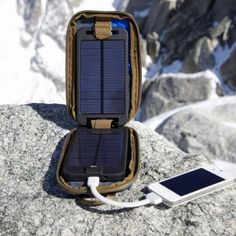 a cell phone is plugged into a charger on top of a rock with mountains in the background