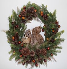 a squirrel is sitting in a wreath with pine cones and acorns