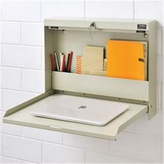 an open laptop computer sitting on top of a white shelf in a wall mounted cabinet