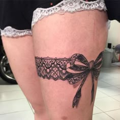 a woman's thigh with a black lace garter and a bow on it