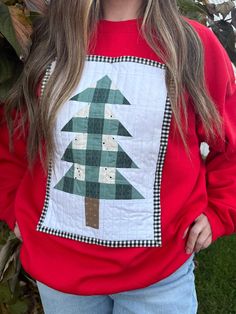 a woman wearing a red sweatshirt with a green christmas tree on the front and plaid trim