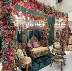 an elaborately decorated room with flowers and chandeliers on the wall, along with couches and chairs