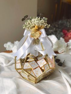 a bouquet of flowers sitting on top of a golden box with white ribbons and tags