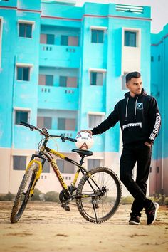 a man standing next to his bike in front of a building with blue paint on it