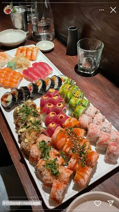 an assortment of sushi on a long white platter