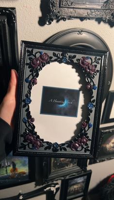 a person holding up a frame with flowers on it