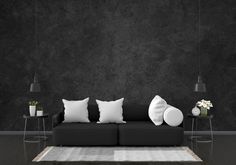 a black and white living room with pillows on the couch, two side tables and one end table