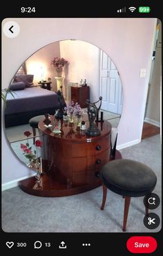 a round mirror sitting on top of a wooden dresser next to a footstool