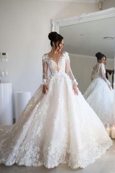 a woman in a white wedding dress looking at herself in the mirror with her hands on her hips