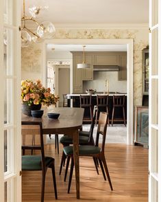 the dining room table is surrounded by chairs and vases with flowers on it,