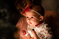 a woman holding a baby next to a christmas tree