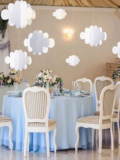 a dining room with blue table cloths and white clouds hanging from the ceiling