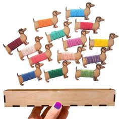 a person is holding a piece of wood with string dachshunds on it