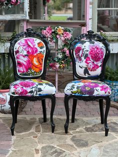 two chairs with floral designs on them sitting in front of a flower potted plant