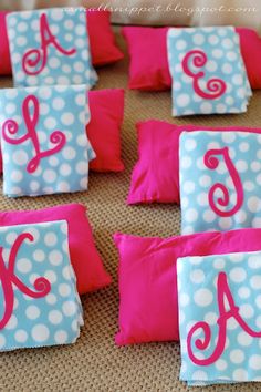 pink and blue polka dot pillows with monogrammed letters on them, sitting on a table