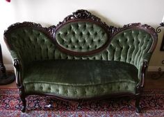 a green velvet couch sitting on top of a rug