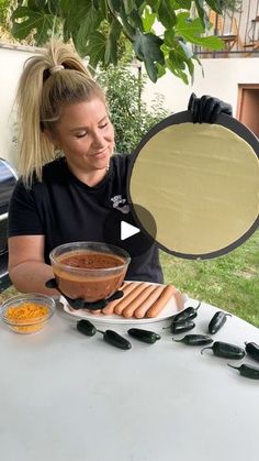 a woman holding up a plate with hot dogs on it and some condiments in front of her