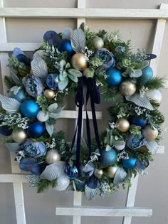 a wreath with blue and silver ornaments hanging on a door