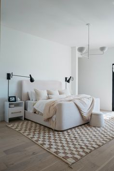 a large bed sitting on top of a wooden floor next to a white dresser and lamp