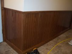 a room that is being remodeled with wood paneling and tile on the floor next to a door