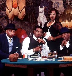 three men and a woman sitting at a table with drinks in front of the camera