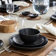 the table is set with black dishes and place settings for two people to sit at