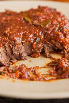 a white plate topped with meat covered in marinara sauce and a fork on top of it