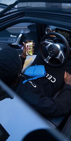 a man sitting in the driver's seat of a car using his cell phone