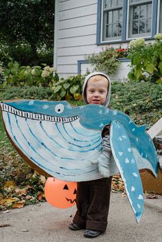 a young boy holding a paper boat shaped like a whale