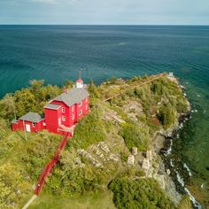 an aerial view of a red house with stairs leading up to the roof and water in the background