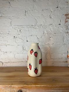 two ceramic vases sitting on top of a wooden table next to a white brick wall