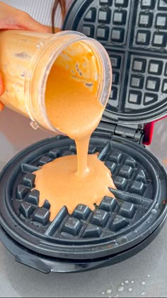 a person pouring orange sauce on top of a waffle