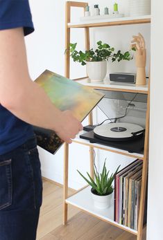 a person holding a record player in front of a bookshelf filled with records