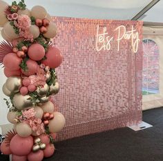 the balloon arch is decorated with pink and gold balloons, greenery, and flowers